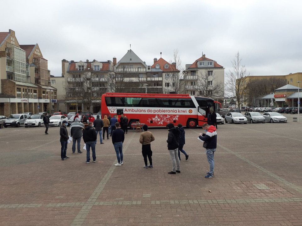 Zdjęcie - autobus do poboru krwi zaparkowany w Murowanej Goślinie, przed nim kolejka kilkudziesięciu osób