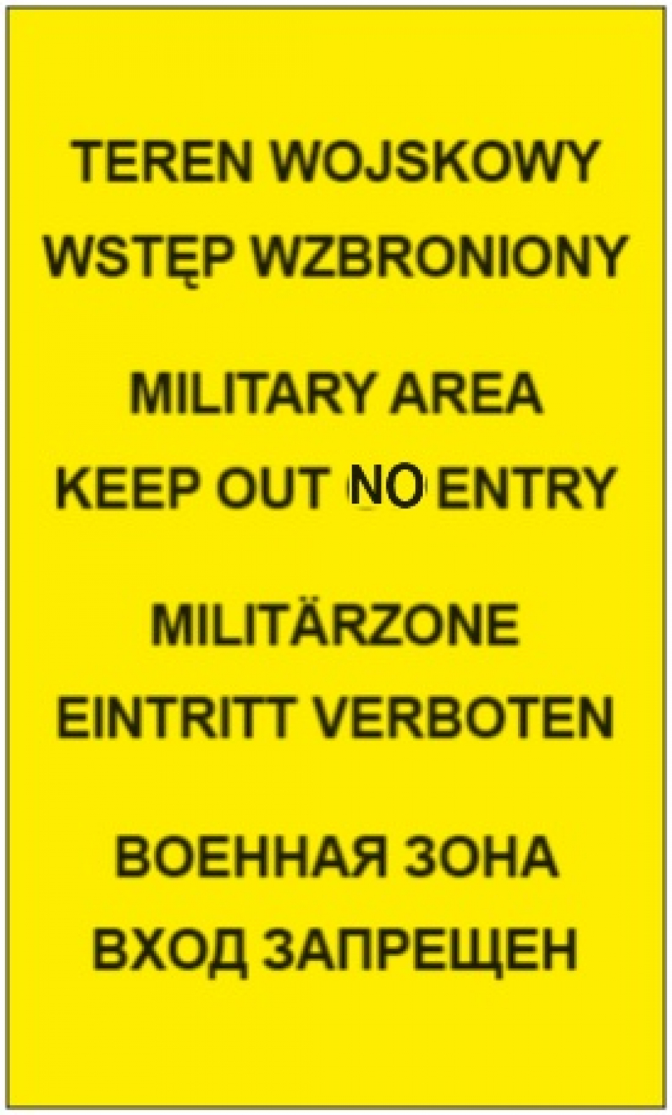 Na tablicy z żółtym tłem znajduje się czarny napis w czterech językach: TEREN WOJSKOWY WSTĘP WZBRONIONY
