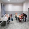 Grupa dzieci z instruktorem przy stołach podczas zajęć „Zabawy plastyczne dla dzieci” w sali Klubu Osiedlowego „Zielone...