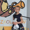 dziecko przy mikrofonie w tle plakat informujący o konkursie, na którym namalowany jest duży miś