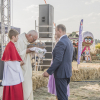 ksiądz całuje bochen chleba, obok ministrant i delegacja sołectwa