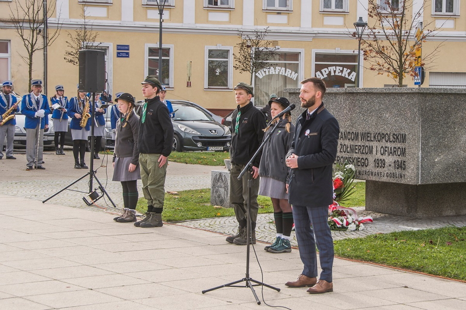 zastępca burmistrza przemawia przy mikrofonie, w tle pomnik