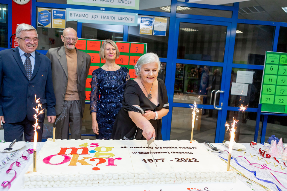 urodzinowy tort, przy nim poprzedni i obecni dyrektorzy ośrodka kultury