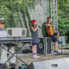 dziewczynka z mikrofonem, obok dwóch muzyków