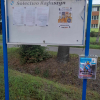 skrzynka na biluetyny z herbem gminy umocowana obok tablicy informacyjnej