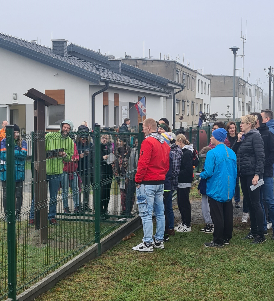 grupa osób przy tablice, w tle budynek świetlicy wiejskiej w Nieszawie