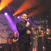 Organizator na scenie, w tle muzycy i wokalistki