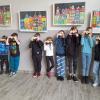 grupa dzieci stoi pod ścianą prezentują własnoręcznie wykonane drewniane aparaty fotograficzne