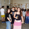 Artystki z grupą kolegów pozują do zdjęcia w tle prace artystów.