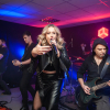 kobieta śpiewa, mężczyźni grają na gitarach