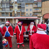 ludzie w strojach mikołajów rozdający upominki z samochodu