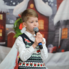 chłopiec z mikrofonem, w tle dekoracje świąteczne