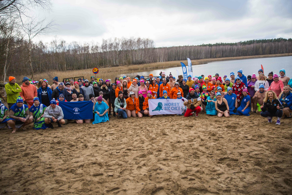 tłum ludzi w strojach kąpielowych pozuje do zdjęcia na plaży