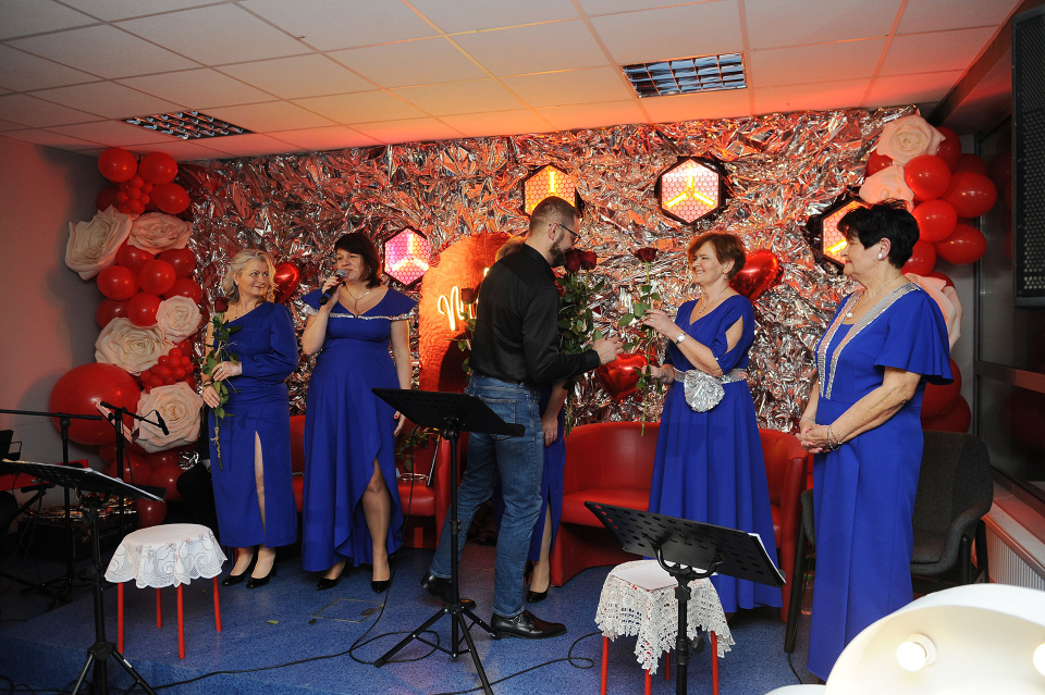 mężczyzna wręcza kobietom na scenie kwiaty