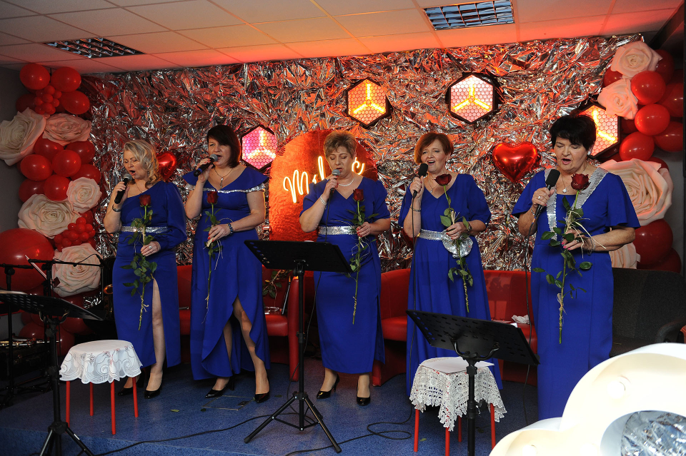 kobiety na scenie śpiewają z kwiatami w dłoni