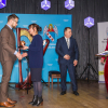 na scenie 4 osoby, mężczyzna odbiera nagrodę na scenie z rąk kobiety