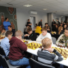 grupa ludzi siedzi przy stolikach i gra w szachy