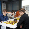 grupa ludzi siedzi przy stolikach i gra w szachy