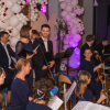 grupa muzyków z instrumentami oraz mężczyzna i kobieta jako konferansjerzy