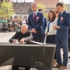 ksiądz dokonuje wpisu w księgę pamiątkową leżącą na stoliku na placu