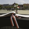 otwarta księga pamiątkowa na stole, w tle ludzie na placu
