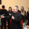 ksiądz z mikrofonem, w tle osoby z chóru
