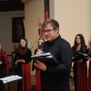 mężczyzna z mikrofonem, w tle osoby z chóru