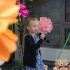 dziewczynka śpiewa na scenie, w tle motywy kwiatowe