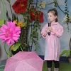 dziewczynaśpiewa na scenie, w tle motywy kwiatowe i rozłożony parasol