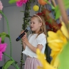 dziewczynka śpiewa na scenie, w tle motywy kwiatowe