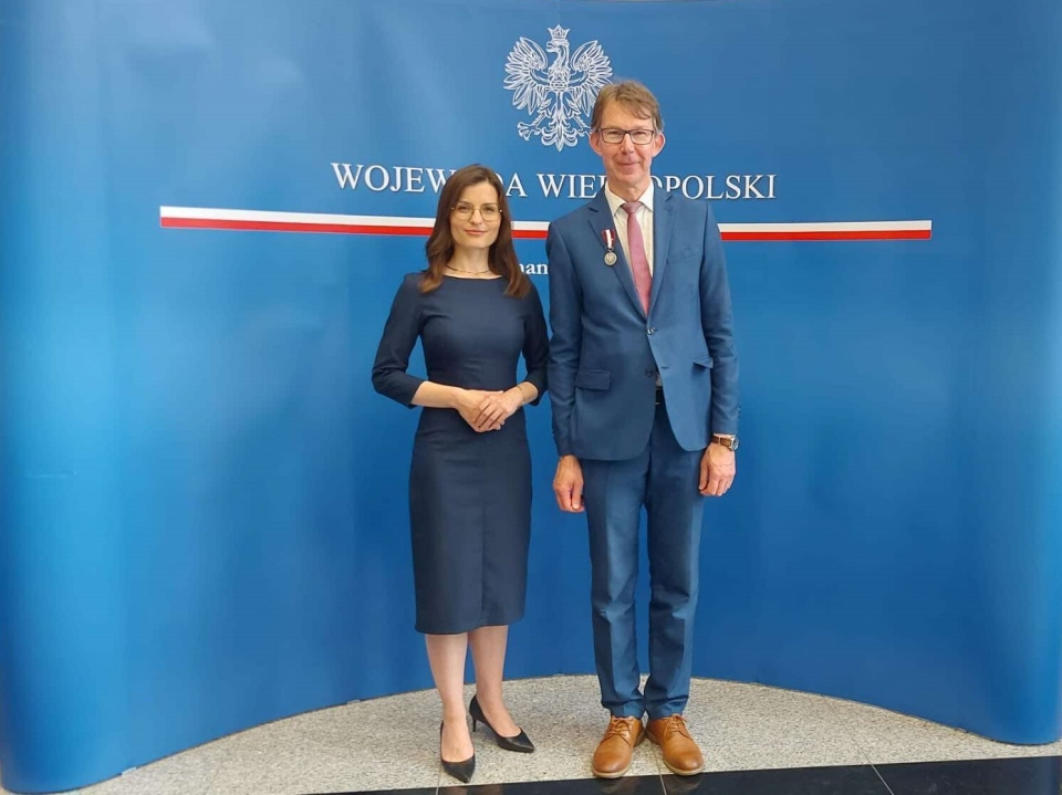 kobieta i mężczyzna na tle ścianki promocyjnej z orłem w tle i napisem Wojewoda Wielkopolski