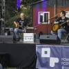trzech mężczyzn na scenie gra na gitarach i śpiewa do mikrofonów