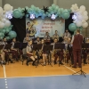 muzycy orkiestry dętej z instrumentami wraz z dyrygentem - na hali widowiskowo-sportowej