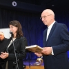 19.	Kobieta przy mikrofonie i mężczyzna z książką.