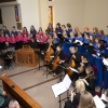 Muzycy grający na instrumentach oraz chóry z dyrygentem przy ołtarzu.