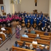 Muzycy grający na instrumentach, chóry przy ołtarzu, uczestnicy koncert w ławkach – zdjęcie z góry.
