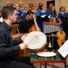 Muzyk grający na instrumentach perkusyjnych w tle chór.