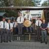 trzy osoby na podium, obok podium grupa ludzi