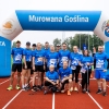 grupa ludzi pozuje do zdjęcia na tle bramy na bieżni