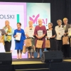 grupa seniorów na scenie trzyma w rękach dyplomy