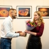Dyrektor CKiS wręcza autorce zdjęć kwiaty,  w tle wystawa.