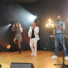 Artysta z mikrofonem, dwie tancerki, muzyk grający na saksofonie oraz DJ na scenie.