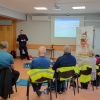policjant stoi i mówi do grupy siedzących seniorów