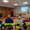 policjant stoi i mówi do grupy siedzących seniorów