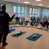 policjant stoi i mówi do grupy siedzących seniorów