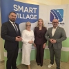 4 osoby pozują do zdjęcia na tle ścianki promocyjnej Smart Village