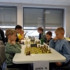 Szachiści przy stołach, szachownice, zegary.