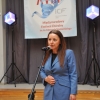Kobieta z mikrofonem, baner festiwalowy w tle.
