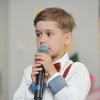 8. Chłopiec w białej koszuli z mikrofonem w ręku.