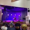 Artysta z gitarą występujący na scenie oraz publiczność.